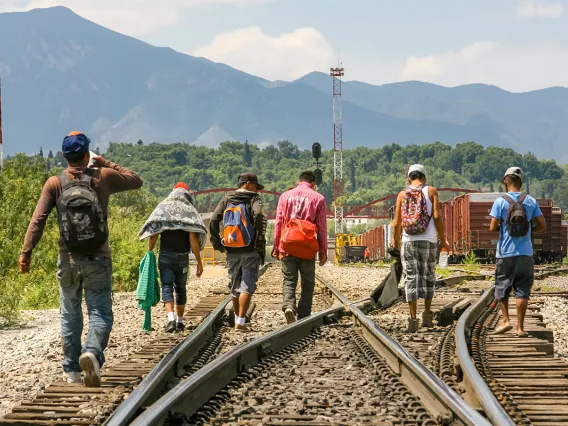 A group of Central American migrants walking along a train track. A group of Central American migrants walking along a train track.