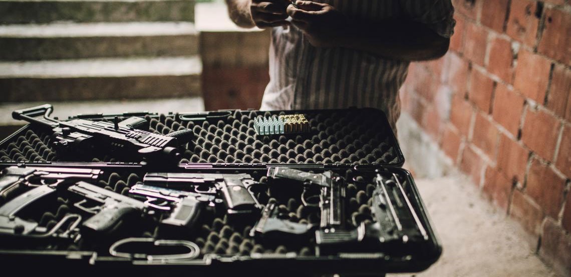 A man examines a table full of guns.
