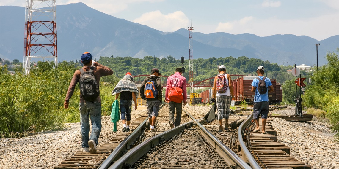 A group of Central American migrants walking along a train track. 