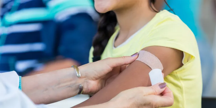 A doctor applying a bandage to a young girl’s arm.