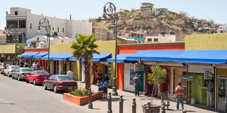 A street full of storefronts and pedestrians in downtown Nogales, Mexico. 