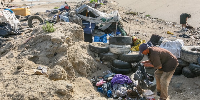 Migrants building shelters made of trash in a canal near the border line between the U.S. and Mexico.